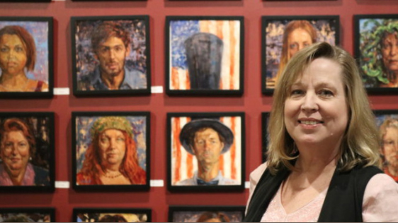 photo of Pamela Wilde with some of her portrait exhibition in the background
