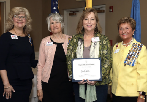 Four women standing, one is holding a certificate